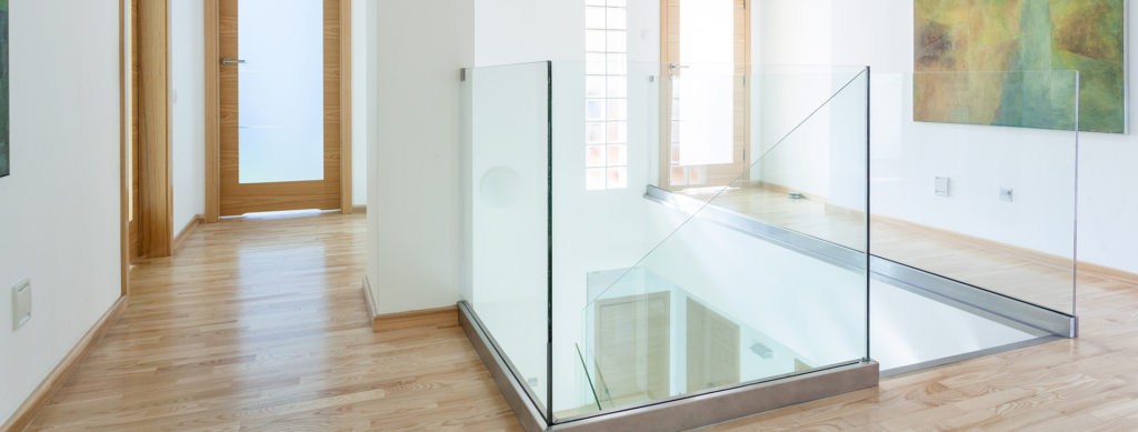 Stairs, glass banister and doors in modern hallway on the attic